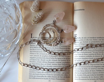 May include: A silver chain necklace with a circular pendant featuring three concentric circles. The pendant is adorned with two pink quartz stones.