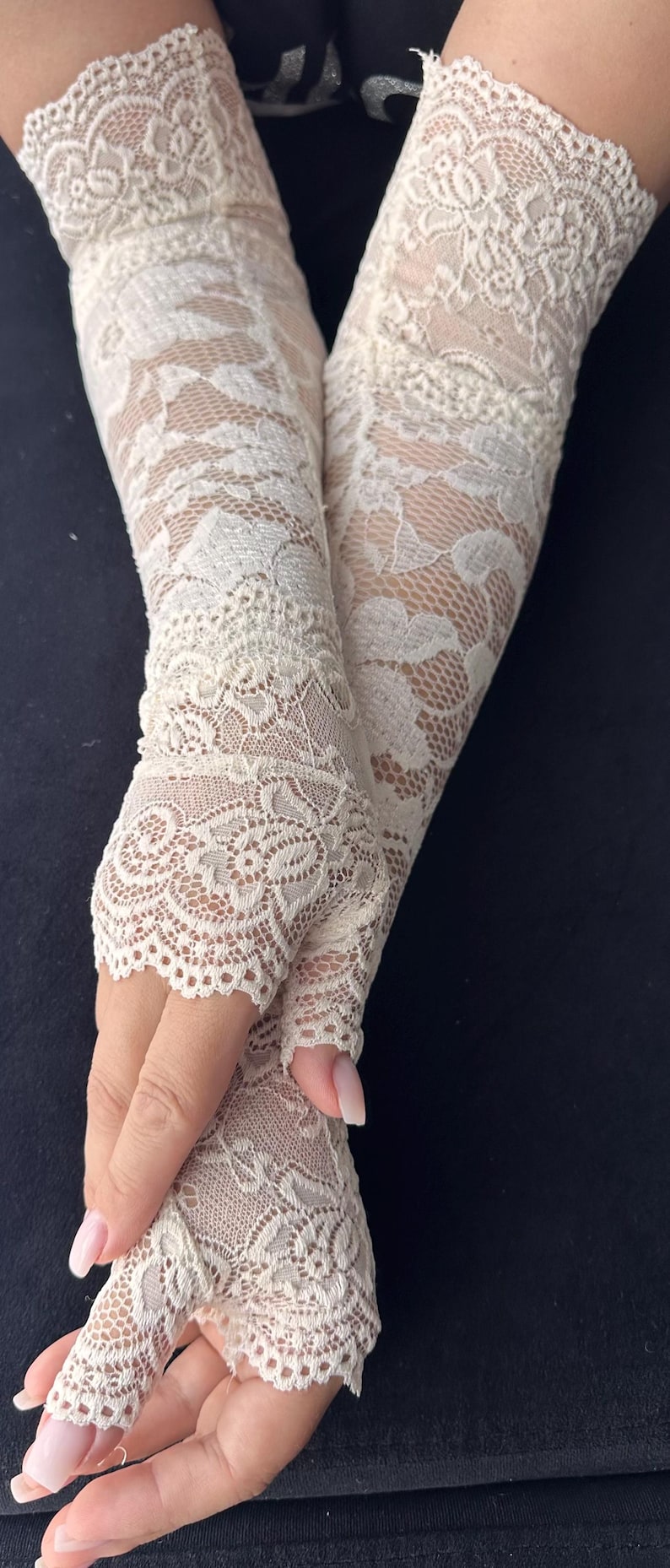 Op de afbeelding: Ivoor kanten vingerloze handschoenen met ingewikkelde bloempatronen. De handschoenen zijn gemaakt van delicate, transparante kant en zijn ontworpen om de hand en onderarm te bedekken, waarbij de vingers vrij blijven.