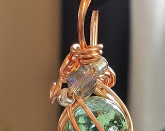 Copper wire wrapped glow in the dark glass marble pendant on a satin adjustable cord. Several colors to choose from.