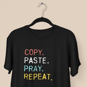 Könnte beinhalten: Schwarzes T-Shirt mit dem Text "COPY. PASTE. PRAY. REPEAT." in bunten Buchstaben.