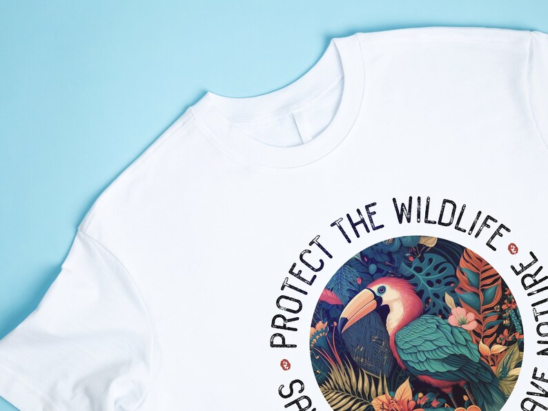 May include: White t-shirt with a circular graphic design featuring a toucan in a jungle setting. The text "PROTECT THE WILDLIFE" is printed around the circle.