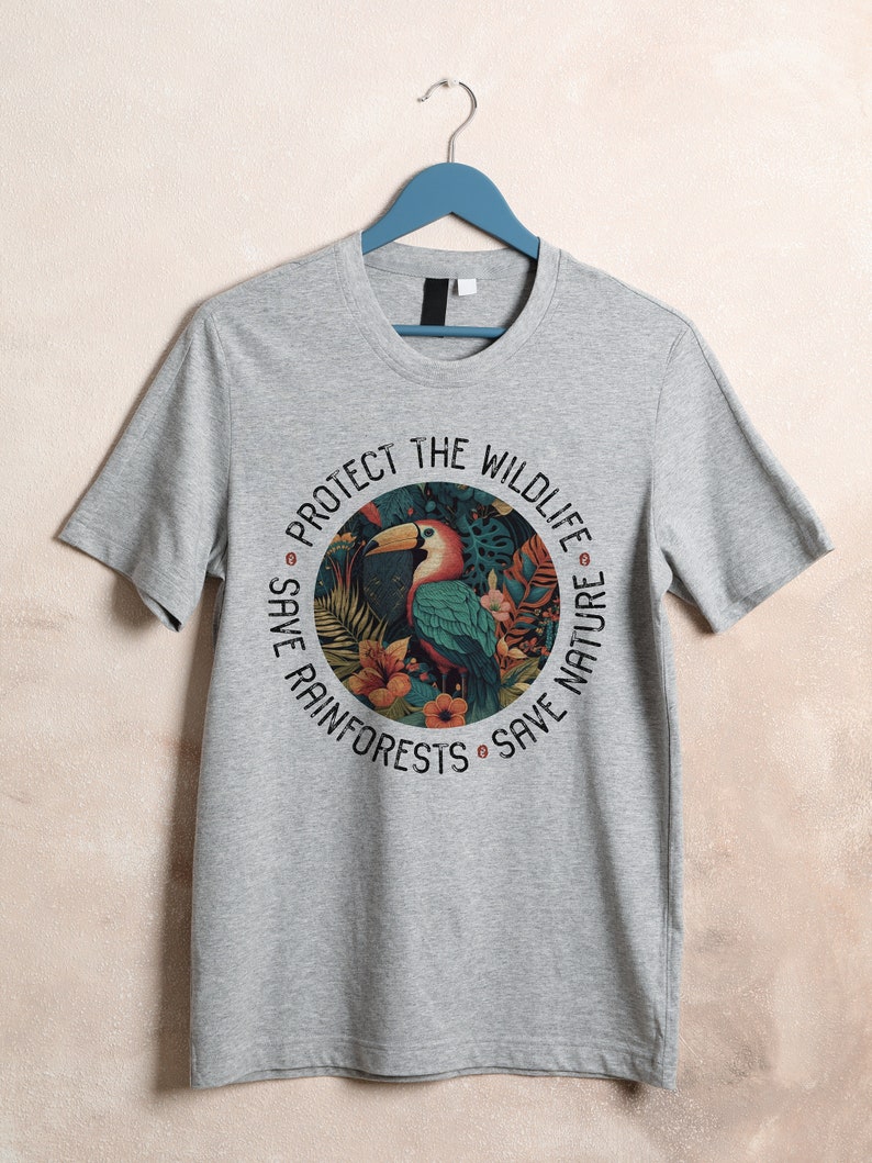 May include: Gray t-shirt with a circular graphic featuring a toucan in a rainforest setting. The text around the graphic reads "Protect the Wildlife, Save Rainforests, Save Nature."