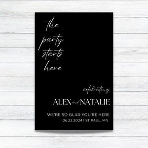 May include: Black and white wedding sign with the text "the party starts here celebrating ALEX and NATALIE WE'RE SO GLAD YOU'RE HERE 06.22.2024 I ST PAUL, MN"