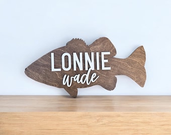 May include: A wooden bass fish cutout with the name "Lonnie Wade" written in white letters.