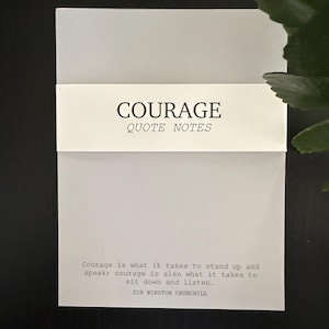 May include: A stack of white quote notes with the word "COURAGE" printed in black. The quote notes have a white band across the middle with the words "QUOTE NOTES" printed below "COURAGE". A quote by Sir Winston Churchill is printed on the bottom.