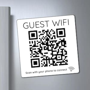 May include: White square sign with the text "GUEST WIFI" and a black and white QR code. The text "Scan with your phone to connect" is below the QR code with a wifi symbol.