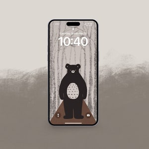 Könnte beinhalten: Eine Illustration eines schwarzen Bären auf einem Telefonbildschirm mit grauem und weißem Hintergrund. Der Telefonbildschirm zeigt die Uhrzeit 10:40 und das Datum Samstag, 10. November.