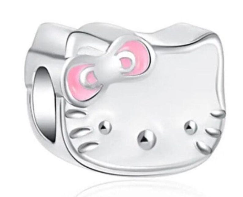 May include: A silver charm in the shape of Hello Kitty with pink ears and a pink bow.