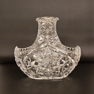 May include: A clear glass bowl with a cut crystal design. The bowl has a handle and is shaped like a basket.