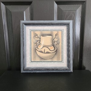 Peut inclure: Une estampe encadrée d'un dessin en noir et blanc d'un vase en poterie amérindien avec des accents orange. Le vase est décoré d'un motif géométrique.
