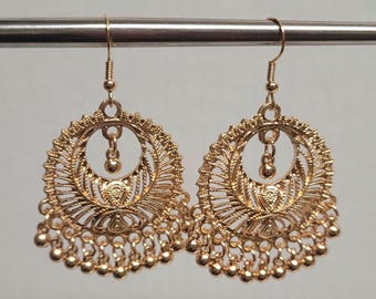 Peut inclure: Une paire de boucles d'oreilles pendantes dorées avec un motif circulaire et une frange de perles. Les boucles d'oreilles ont un motif délicat et complexe et sont parfaites pour ajouter une touche d'élégance à n'importe quelle tenue.