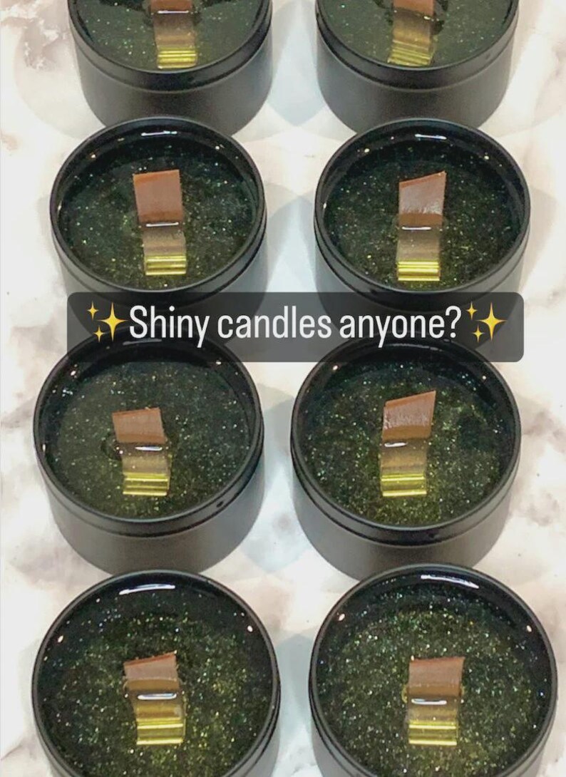 May include: Several small, round, black containers filled with a dark green substance and a wooden wick. The text "Shiny candles anyone?" is displayed in a white font with star accents.