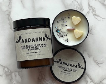 May include: Two black candle jars with white labels. The labels have a black dragon design and the text "Andarna" and "Just because I'm small doesn't mean I'm not powerful". One jar has a white lid with a white heart design.