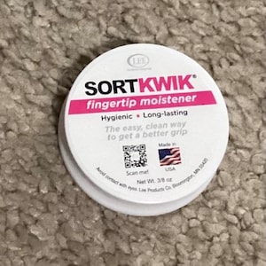 May include: White container with a pink label that says "SORTKWIK fingertip moistener". The label also says "Hygienic Long-lasting" and "The easy, clean way to get a better grip". There is a QR code and the words "Scan me!" and "Made in USA".