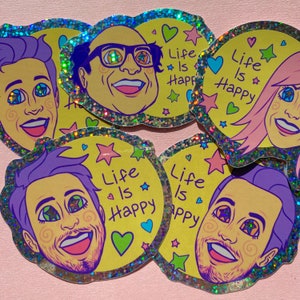 Puede incluir: Una colección de pegatinas coloridas con retratos de dibujos animados con ojos en forma de estrella. Cada pegatina tiene un fondo amarillo con el texto "Life Is Happy", corazones y estrellas. Las pegatinas tienen un borde plateado brillante.