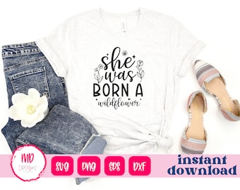 May include: White t-shirt with black text that reads "She was born a wildflower" with a small flower graphic above the text.