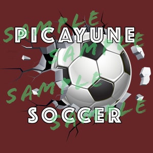 May include: A white and black soccer ball breaking through a cracked red wall. The words "SPICAYUNE" and "SOCCER" are written in white letters on the wall.