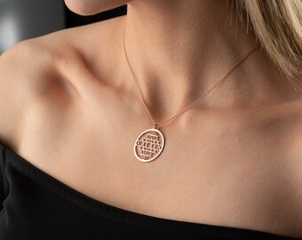 May include: A rose gold necklace with a circular pendant featuring a geometric design. The pendant is made of delicate wire and has a detailed pattern of triangles and squares.