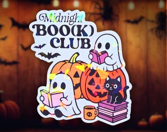 Könnte beinhalten: Ein holografischer Aufkleber mit dem Text Midnight BOO(K) CLUB, zwei weißen Geistern, die rosa Bücher lesen, zwei orangefarbenen Kürbissen, einer schwarzen Katze auf einem Stapel violetter Bücher, einer kleinen orangefarbenen Tasse mit Totenkopf und Fledermäusen.