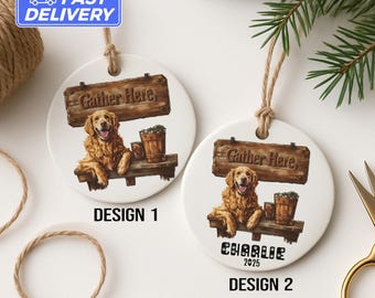 Könnte beinhalten: Zwei runde Hundeornamente aus weißer Keramik mit Aquarelldesign. Jedes Ornament zeigt einen Golden Retriever, ein Holzschild mit der Aufschrift "Gather Here" und einen kleinen Holzeimer. Ein Ornament sagt "Charlie 2025".