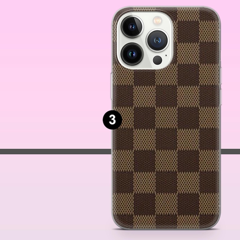 May include: A brown and tan checkered phone case with a clear border. The case has a camera cutout and the number 3 in a black circle. The background is a gradient of pink and white.