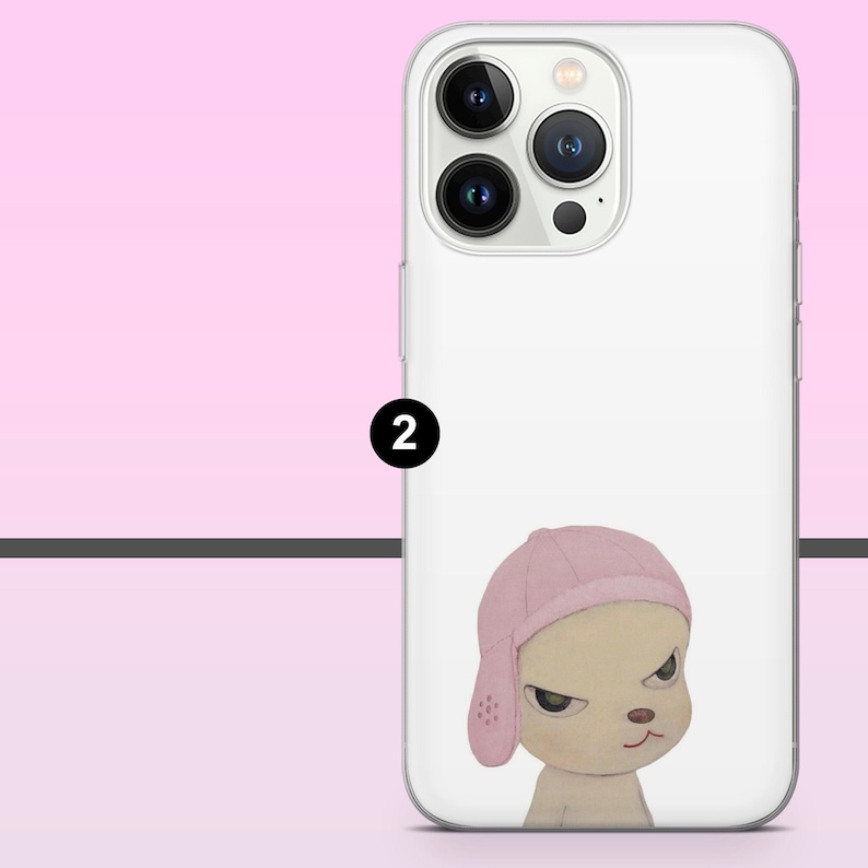 May include: White phone case featuring a cartoon illustration of a dog wearing a pink cap. The dog has a stern expression and is set against a white background. The phone case has a clear camera lens area.