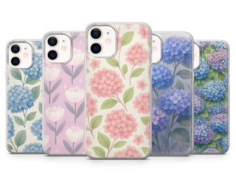 Op de afbeelding: Vijf verschillende telefoonhoesjes met bloemenmotieven. De hoesjes zijn transparant en laten het ontwerp van de telefoon door de hoes heen zien. De ontwerpen omvatten roze en witte bloemen, blauwe bloemen en een roze en wit bloemenpatroon.