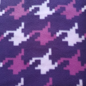 May include: Purple fleece fabric with a pink and white camouflage pattern. The fabric is soft and fuzzy, and it would be perfect for making blankets, scarves, or other cozy items.