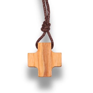 May include: A wooden cross pendant with a brown cord. The cross is light brown with a natural wood grain. The cord is knotted at the top, and the cross hangs below. The background is white.