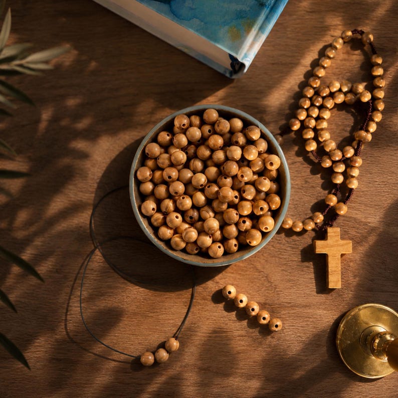 Wooden beads in a bowl with a rosary and bible on a brown surface