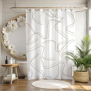 May include: White shower curtain with a black and gold wavy line pattern. The curtain hangs from a gold-colored rod. The bathroom has a wooden floor, a round mirror, and a potted plant.