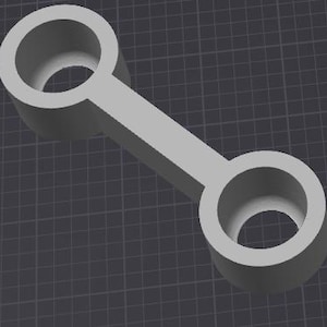 May include: A grey plastic connector with two circular openings. The connector is designed for joining two pieces together.