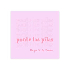May include: A square, light pink print with the phrase "ponte las pilas" repeated in a faded pink font. The words "ponte las pilas" are in a darker pink font in the center. The phrase "Porque Si Se Puede" is at the bottom.