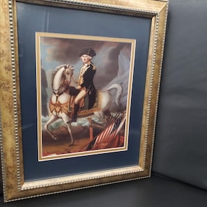 A framed, double matted print of a historic painting of General George Washington on horseback.