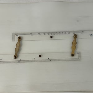 May include: Transparent plastic navigation tool with measurements and the text "CAPT FIELDS". It features two wooden handles and is designed for plotting courses. Used for navigation and plotting courses.