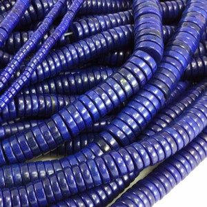 May include: A strand of deep blue lapis lazuli beads, each bead is a stack of small, round discs. The beads are arranged in a loose pile, showing the texture and color of the stone.