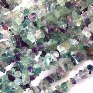 May include: A strand of multi-colored fluorite chip beads. The beads are a mix of green, purple, and blue shades. The beads are irregular in shape and size.