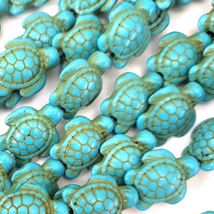 May include: A strand of turquoise blue sea turtle beads. The beads are made of a smooth, polished stone and have a detailed turtle design.