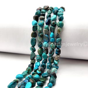 May include: Strands of turquoise-colored gemstone beads. The beads are irregular in shape and vary in shades of blue, green, and brown. The beads are strung together, creating a textured and colorful display. Ideal for jewelry making.