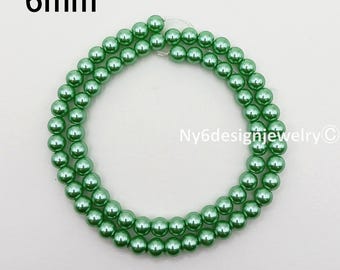 May include: Strands of 6mm green beads, likely for jewelry making. The beads are a consistent size and color, with a glossy finish. The text "6mm" is in the upper left corner. The text "Ny6designjewelry" is in the lower right corner.