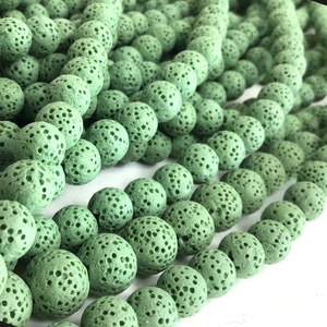 May include: A strand of green lava rock beads. The beads are round and have a porous texture.