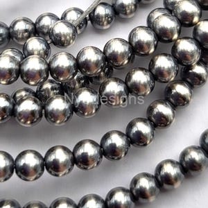 May include: A strand of silver-toned round pearls. The pearls have a smooth, shiny finish.