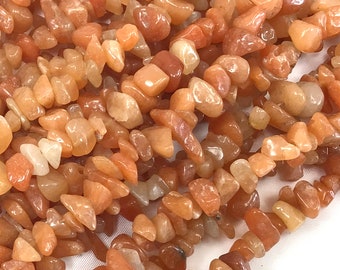 May include: A strand of orange carnelian chip beads. The beads are irregular in shape and have a natural, polished finish.