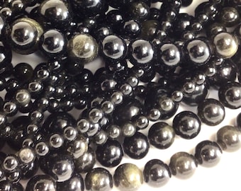 May include: A strand of black gemstone beads with a golden sheen. The beads are round and smooth, and they are arranged in a loose pile.