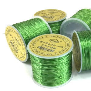 May include: Green elastic cord spools with yellow labels that read "Crystal Line" and "Polyurethane 100% Japanese Water Thread".