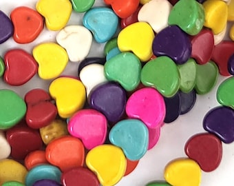 May include: A strand of colourful heart-shaped beads made of turquoise. The beads are in various shades of red, orange, yellow, green, blue, purple, and white.