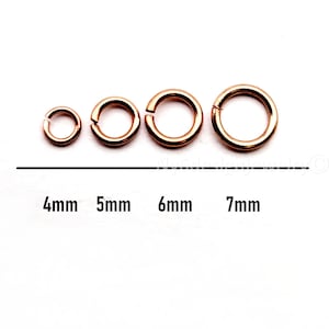 May include: Four rose gold jump rings of varying sizes, from 4mm to 7mm, are displayed in a row. The sizes are labeled below each ring. The rings are open, ready for use in jewelry making or other crafts.
