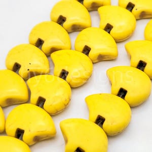 May include: A strand of yellow gemstone beads in a heart shape with a hole in the center of each bead.