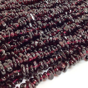 May include: A strand of dark red garnet chip beads. The beads are small and irregular in shape, with a glossy finish.