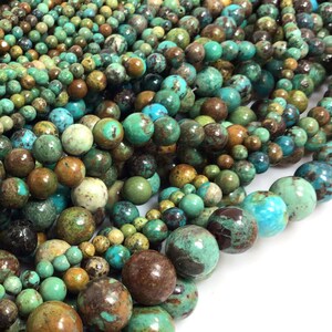 May include: A close-up of a strand of turquoise beads. The beads are a mix of green, blue, and brown colors. The beads are round and have a smooth, polished finish.